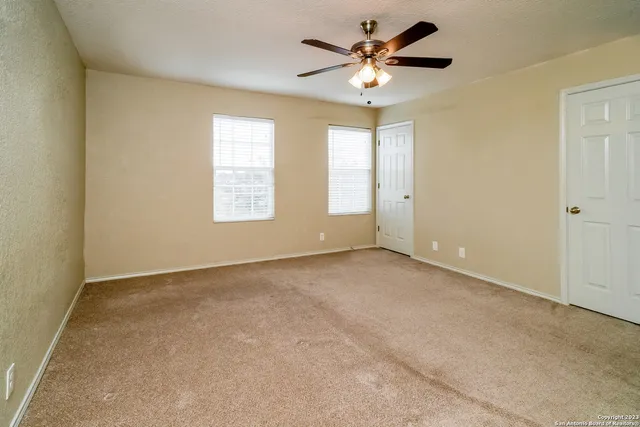 an empty room with windows and fan