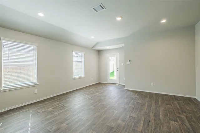 an empty room with wooden floor and windows