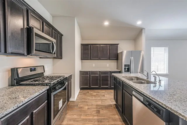 a kitchen with stainless steel appliances granite countertop a stove a sink and a microwave