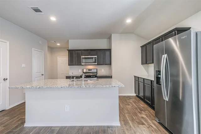 a kitchen with stainless steel appliances granite countertop a sink refrigerator and cabinets