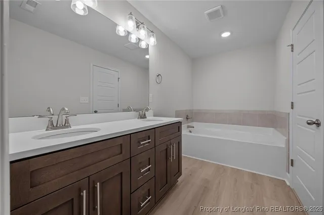 a bathroom with a tub double sink and mirror