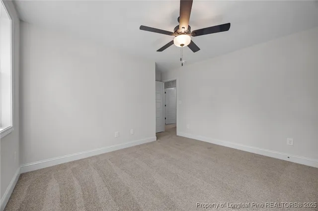 a view of an empty room with a chandelier fan
