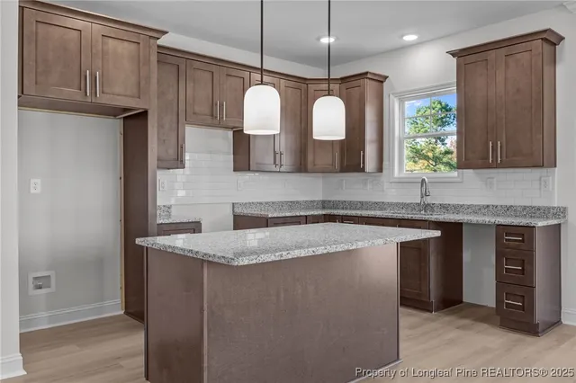 a kitchen with kitchen island granite countertop a sink a counter space appliances and cabinets