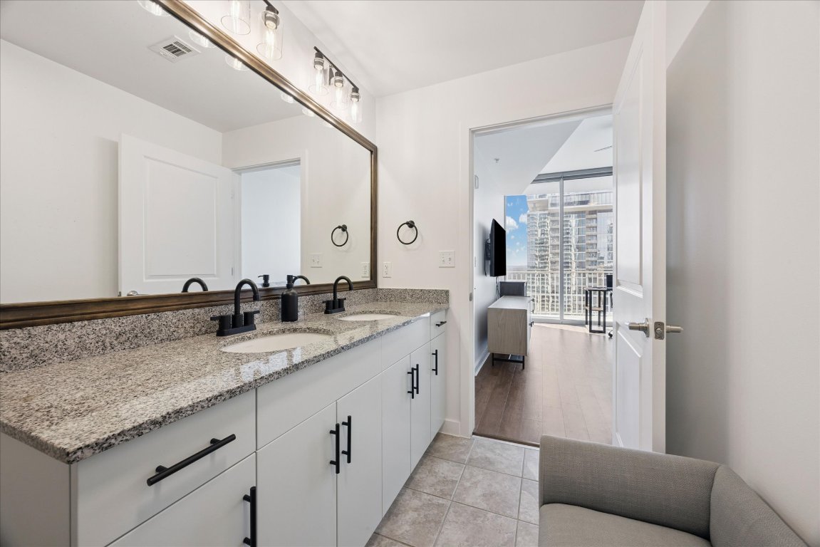 360 Nueces Street, Unit 2704 Austin, TX 78701 - Photo 22 of 40 a spacious bathroom with a granite countertop sink and a mirror