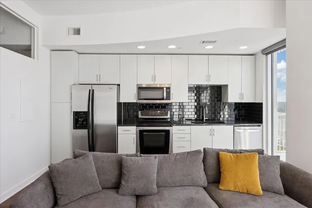 a living room with stainless steel appliances kitchen island a refrigerator and a couch