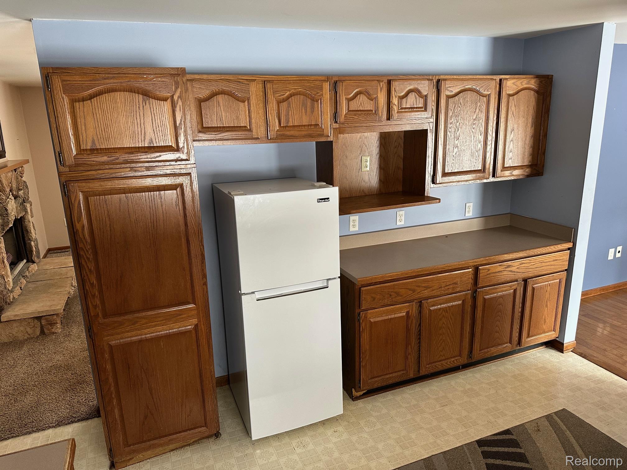 3803 Warner Road Cass City, MI 48726 - Photo 49 of 85 Kitchen with freestanding refrigerator, brown cabinetry, light flooring, and a fireplace