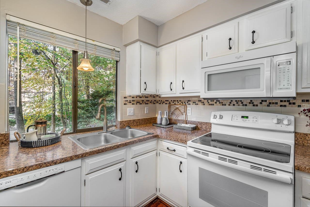 3080 Colony Road, Unit 3080E Durham, NC 27705 - Photo 12 of 31 a kitchen with granite countertop a sink stainless steel appliances and white cabinets
