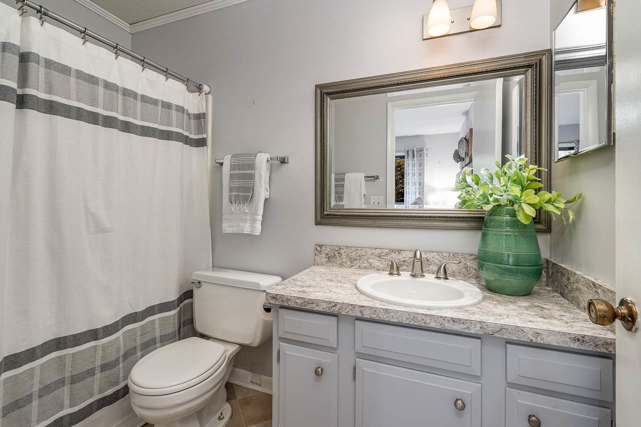 3080 Colony Road, Unit 3080E Durham, NC 27705 - Photo 21 of 31 a bathroom with a granite countertop sink a toilet and a mirror