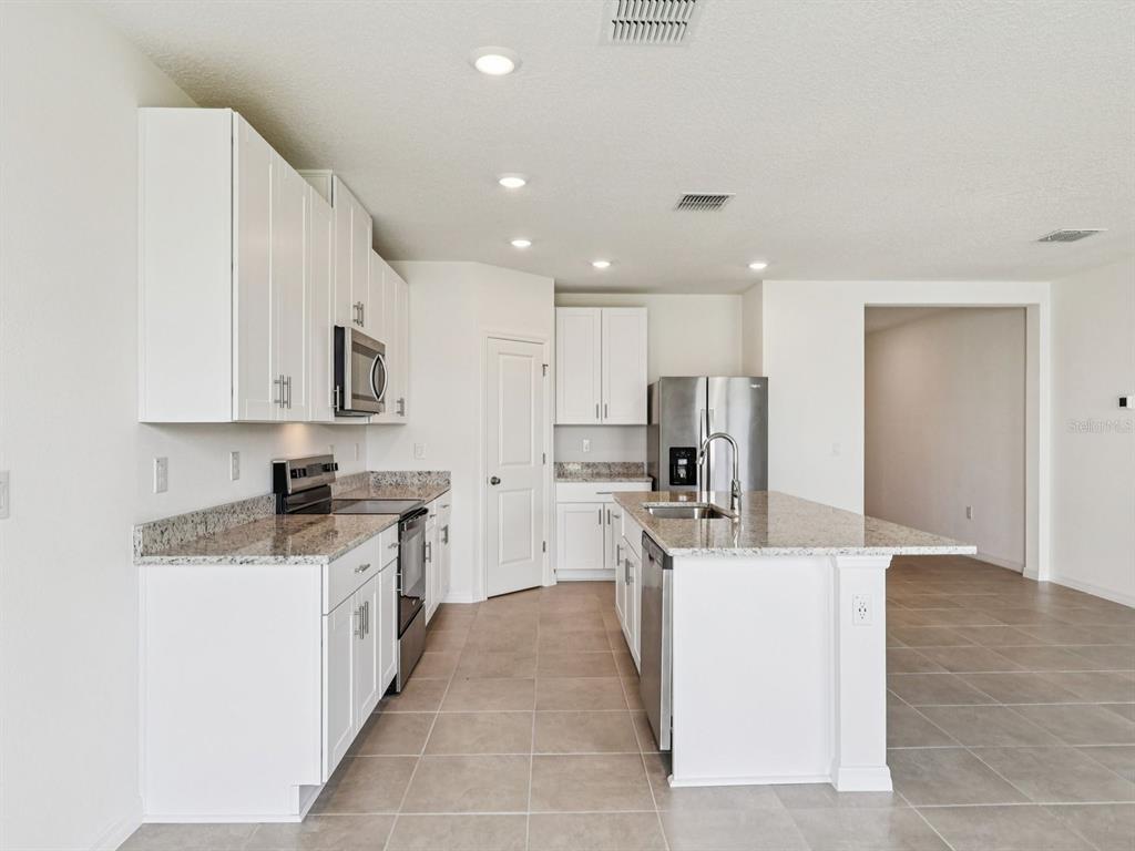 1646 Bark Rdg Drive Auburndale, FL 33823 - Photo 14 of 34 a kitchen with stainless steel appliances kitchen island sink refrigerator and cabinets