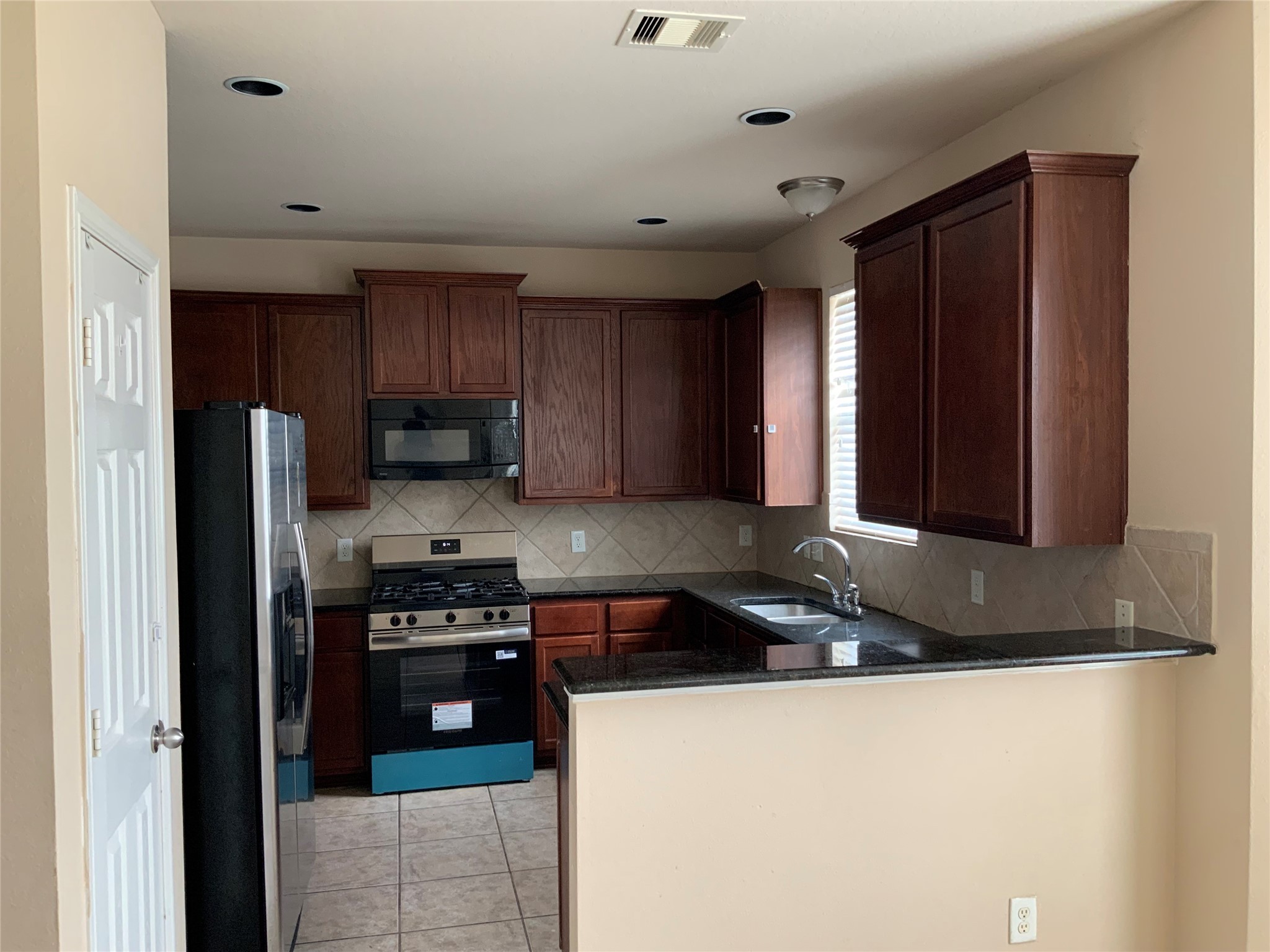 22011 Castle Hawk Trail Richmond, TX 77407 - Photo 18 of 18 a kitchen with stainless steel appliances granite countertop a stove a sink and a refrigerator with wooden cabinets