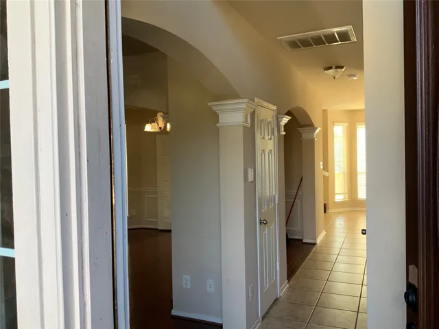 a view of a hallway with wooden floor and a bathroom