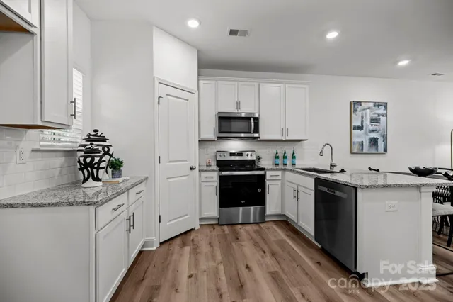 a kitchen with granite countertop a sink stove and refrigerator