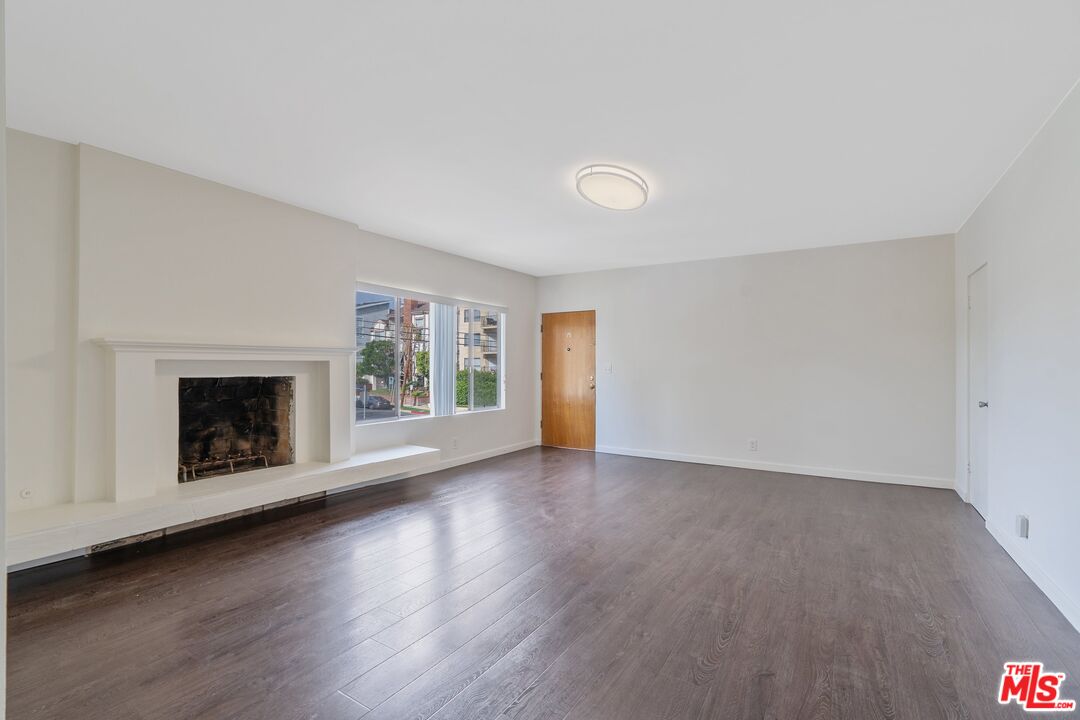 an empty room with wooden floor and a fireplace