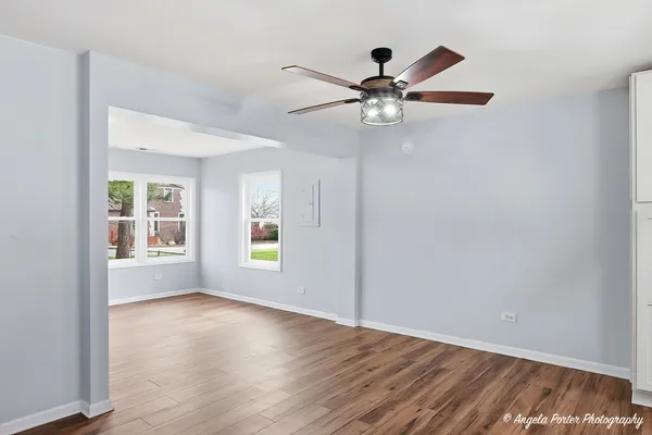 an empty room with wooden floor fan and windows