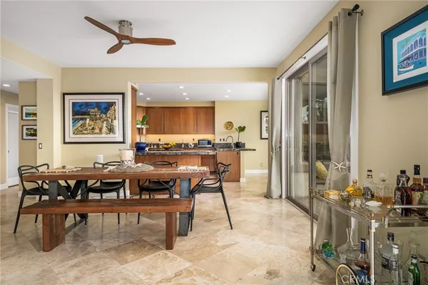 a kitchen with stainless steel appliances granite countertop a refrigerator a sink a stove a dining table and chairs with wooden floor