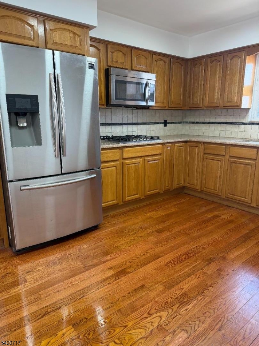 a kitchen with granite countertop a refrigerator and a stove top oven
