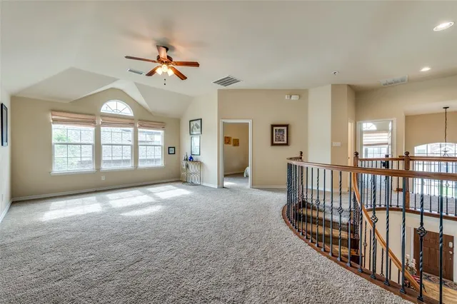 an empty room with windows and ceiling fan