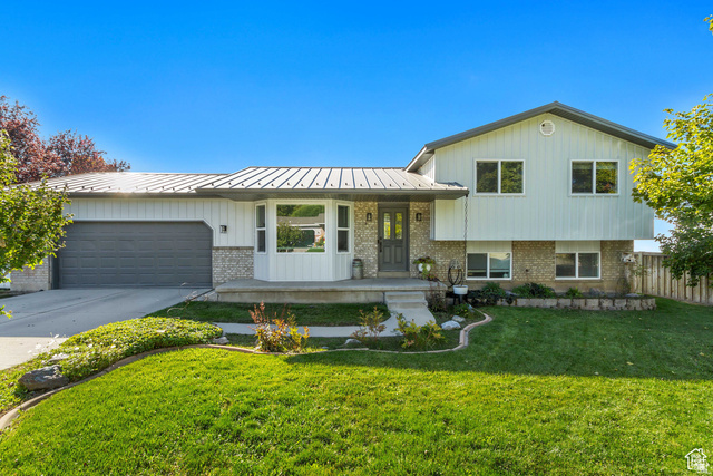 415 360 East Salem, UT 84653 - Photo 20 of 20 Split-level exterior featuring light vertical siding and stone accents, a gray garage door, and a prominent bay window