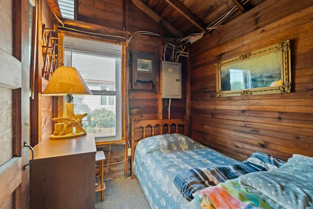 a bedroom with wooden floor and a window