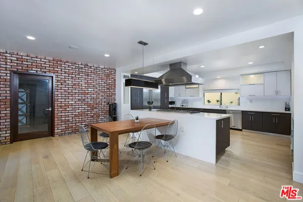 a kitchen with stainless steel appliances kitchen island granite countertop a table chairs sink and cabinets