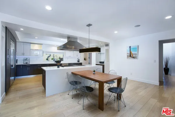 a kitchen with stainless steel appliances a dining table chairs and wooden floor