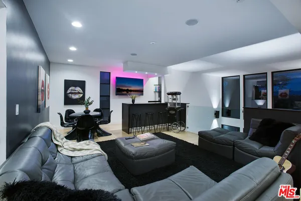 a living room with furniture kitchen view and a wooden floor