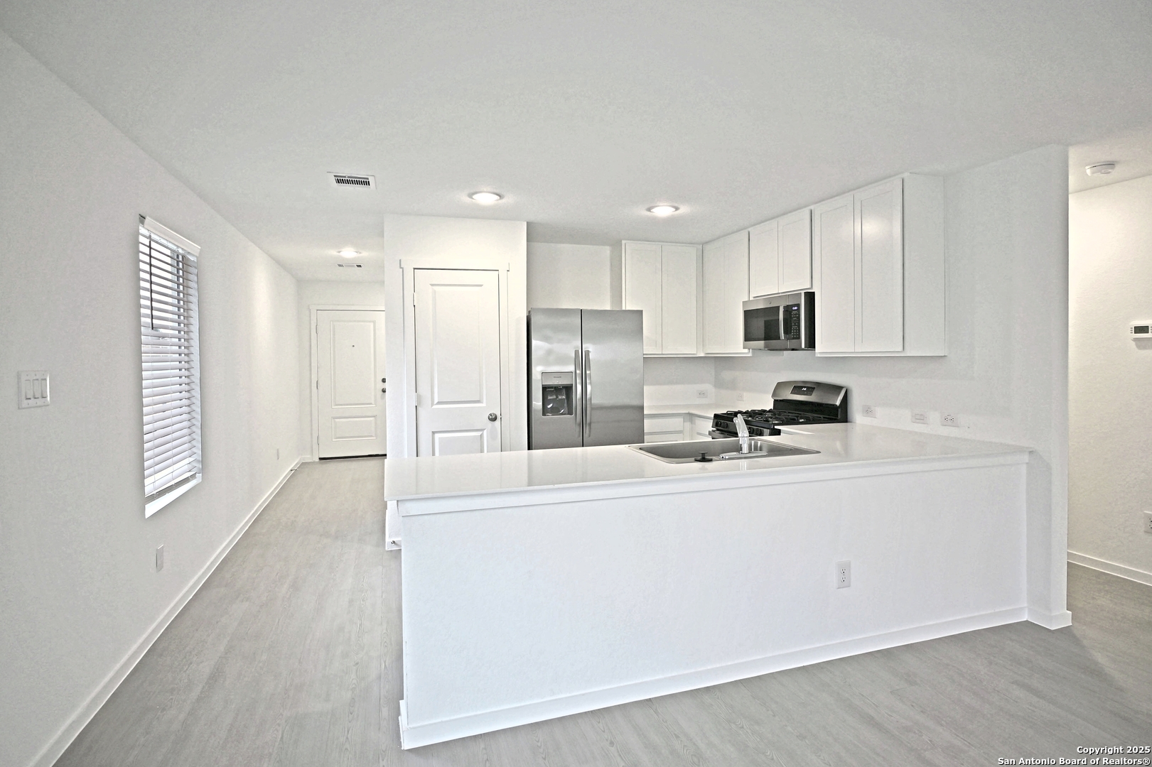 3805 Swift Fox Road New Braunfels, TX 78132 - Photo 3 of 27 a kitchen with stainless steel appliances granite countertop a refrigerator a stove a sink and white cabinets with wooden floor