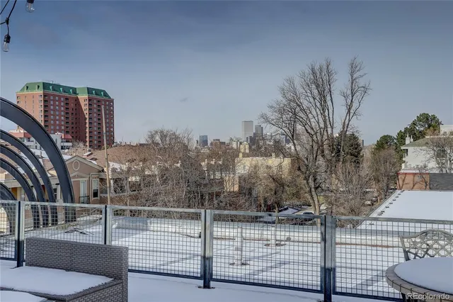 a view of roof deck with couches and wooden fence