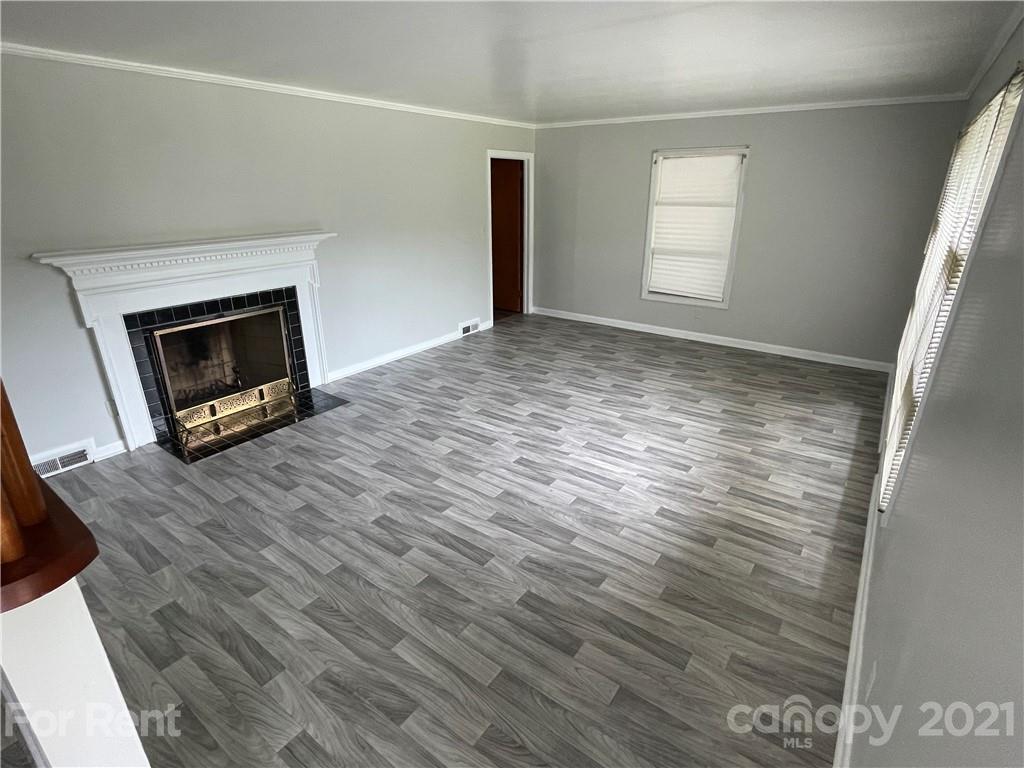 7125 Pence Road, Unit 2 Charlotte, NC 28215 - Photo 5 of 16 an empty room with wooden floor fireplace and windows