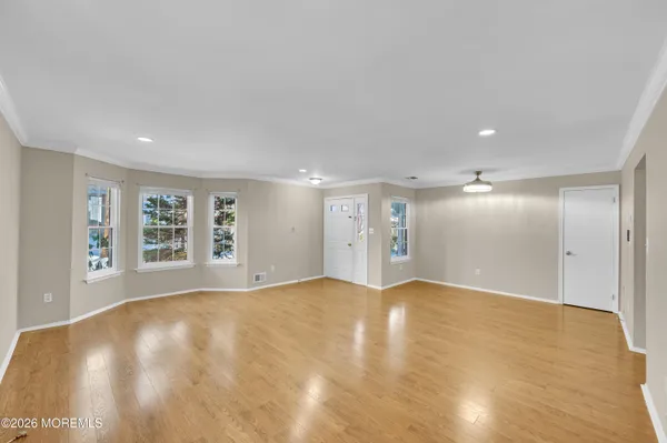 a view of an empty room with wooden floor and a window