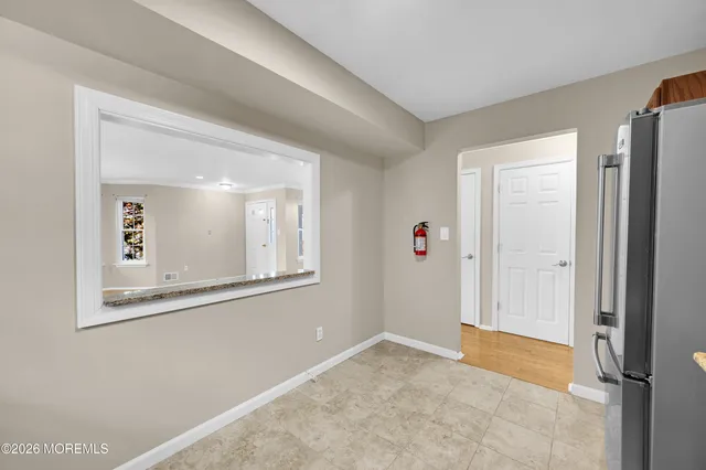 a view of an empty room with window and wooden floor