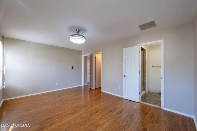 an empty room with wooden floor and bathroom