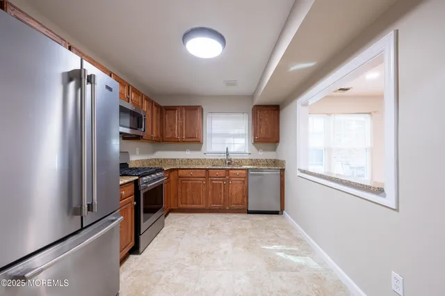a kitchen with stainless steel appliances granite countertop a refrigerator sink and wooden cabinets