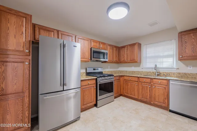 a kitchen with stainless steel appliances granite countertop a refrigerator stove a sink dishwasher and microwave