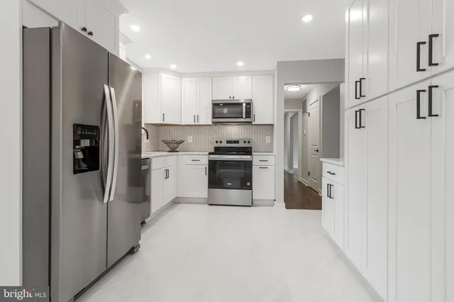 a kitchen with white cabinets and stainless steel appliances