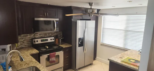 a kitchen with stainless steel appliances granite countertop a refrigerator a stove and a sink with wooden floor