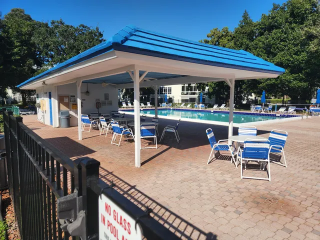 a view of a patio with table and chairs under an umbrella with a barbeque