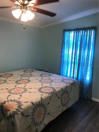 a bed sitting in a bedroom next to a window and a chandelier