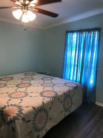 a bed sitting in a bedroom next to a window and a chandelier
