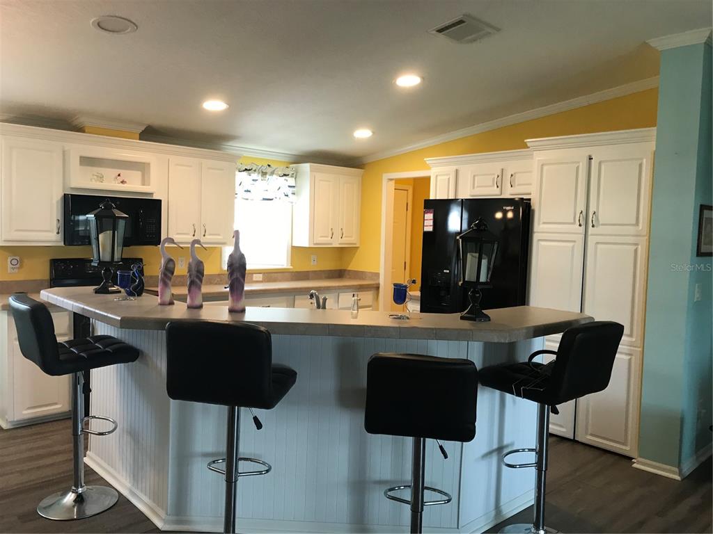 1081 6th Street Okeechobee, FL 34974 - Photo 2 of 22 a kitchen with stainless steel appliances kitchen island granite countertop a table chairs in it and wooden floors