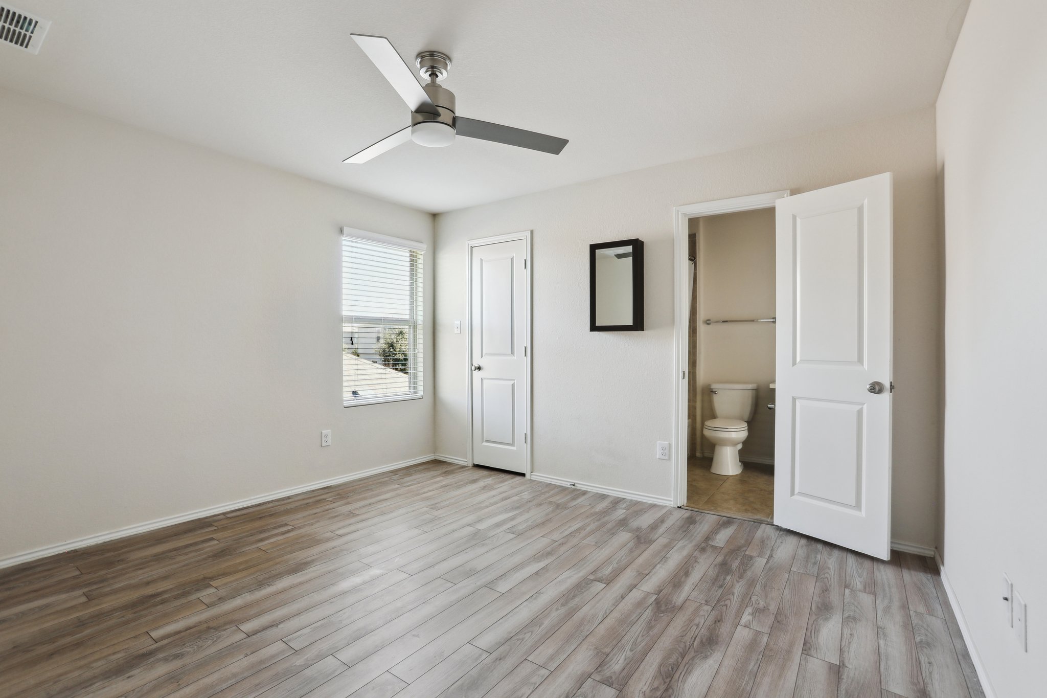 5713 Kennedy Street Austin, TX 78747 - Photo 18 of 30 Unfurnished bedroom with light wood-type flooring, ceiling fan, and connected bathroom