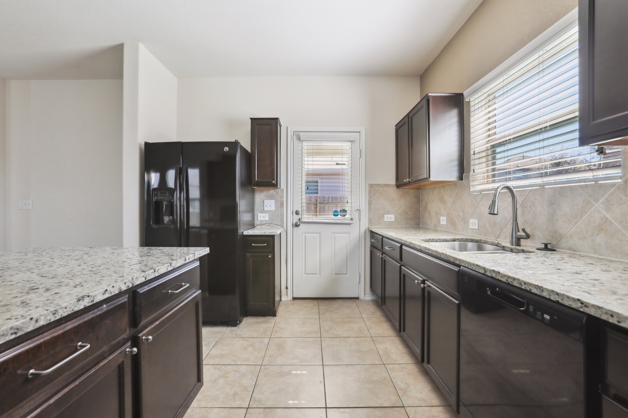 5713 Kennedy Street Austin, TX 78747 - Photo 4 of 30 Kitchen featuring black appliances, light stone countertops, dark wood finish cabinetry, and light tile patterned flooring