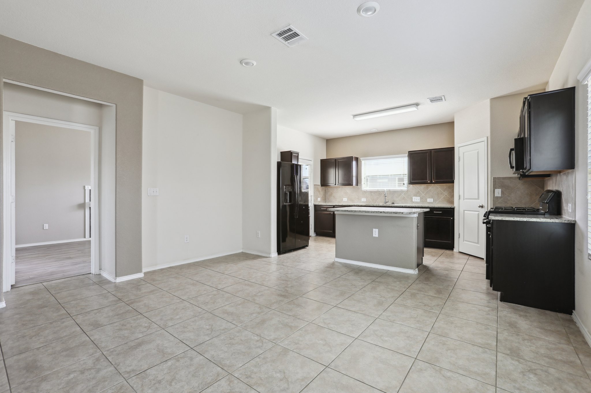 5713 Kennedy Street Austin, TX 78747 - Photo 5 of 30 Kitchen with black appliances, a kitchen island, tasteful backsplash, and light tile patterned floors