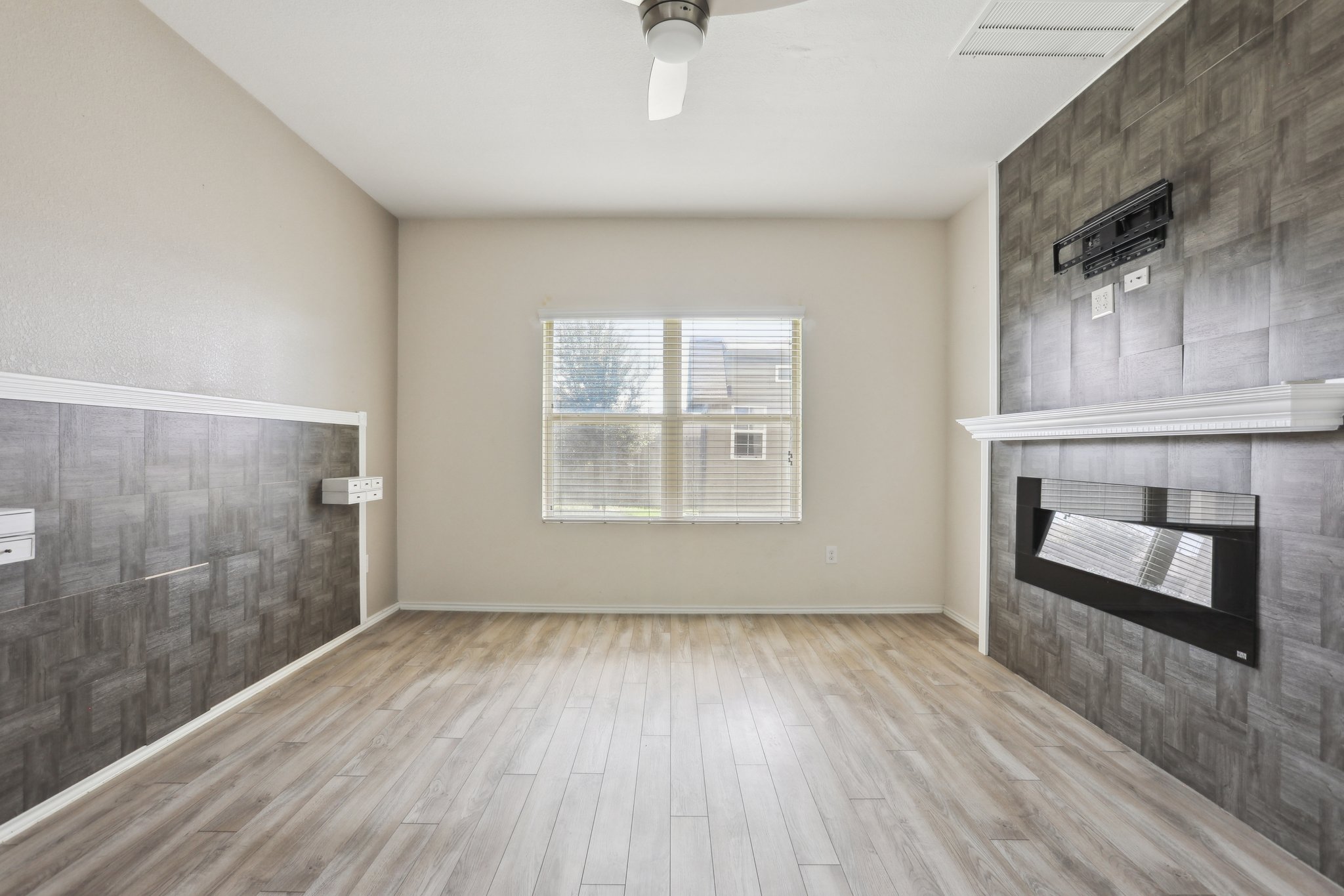 5713 Kennedy Street Austin, TX 78747 - Photo 9 of 30 Unfurnished living room with a fireplace, light wood-style flooring, ceiling fan, and an accent wall