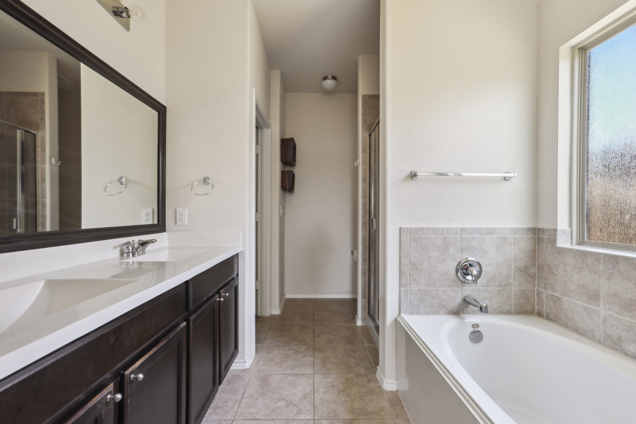5713 Kennedy Street Austin, TX 78747 - Photo 10 of 30 Bathroom with double vanity, a shower stall, a garden tub, and light tile patterned floors