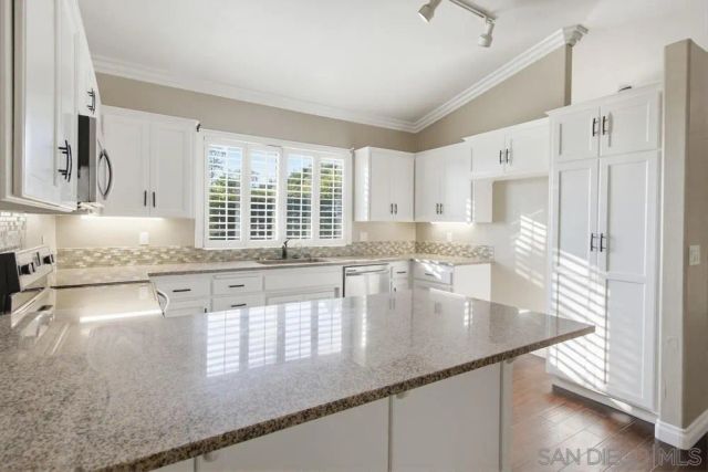 a kitchen with stainless steel appliances granite countertop a sink window and cabinets