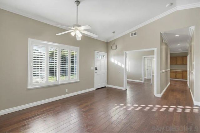 a view of an empty room with a window and wooden floor