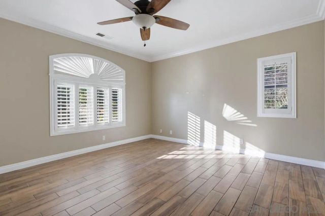 a view of empty room with wooden floor and fan