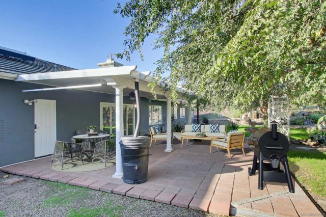 a view of a patio with table and chairs potted plants and a large tree