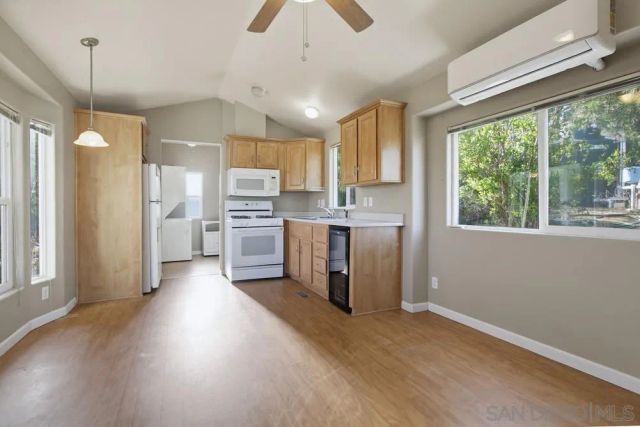 a view of an empty room with a kitchen and a window